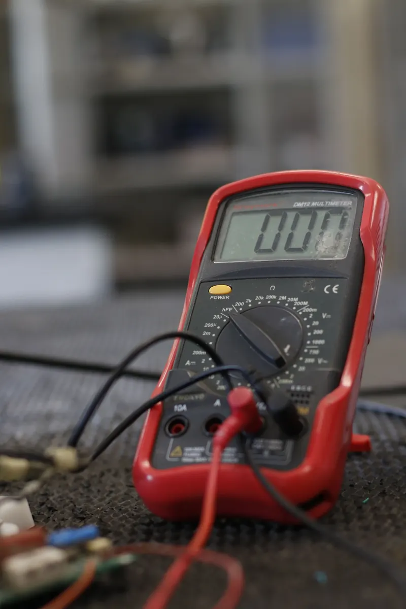 A digital multimeter standing on a workshop bench