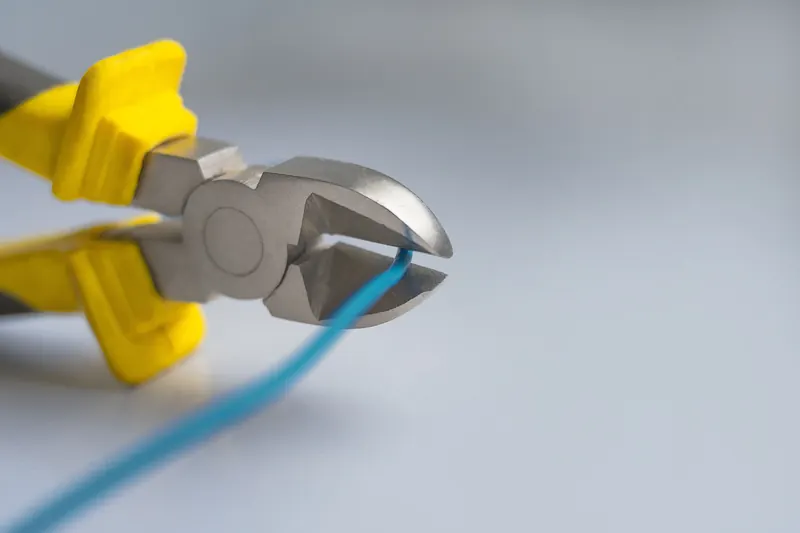 Side cutters around a blue electrical wire